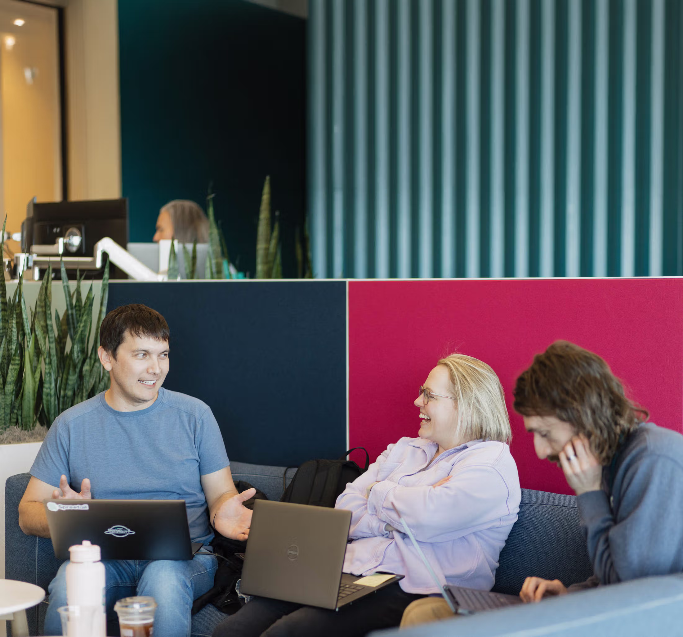 Four people standing and leaning against a ping pong table in a modern office space.